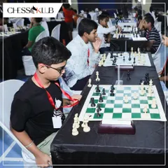 Young competitors, wearing their participant lanyards, concentrate on their boards during a large tournament, showcasing the serious and professional atmosphere.
