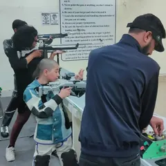 I am providing one-on-one guidance to a young rifle shooter during a practice match. Individual attention is key to correcting form and improving performance.