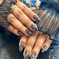 An example of elegant and sophisticated nail art. These almond-shaped nails feature a sheer, translucent base with delicate black floral patterns, creating a beautiful lace-like effect that is both subtle and intricate.