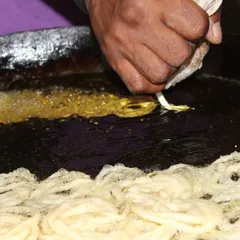 A close-up of our chef skillfully piping jalebi batter into hot oil. This is how we create those perfect, syrupy swirls that are a staple of any celebration.
