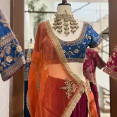 A detailed shot of the blue blouse and orange dupatta, highlighting the delicate embroidery and the beautiful contrast of colors.