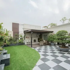 This is what a modern, functional, and beautiful terrace looks like. We combined bold checkered flooring with soft, natural grass and a variety of tropical plants to create a space that feels both expansive and intimate, complete with a covered seating area and a custom bonsai feature.