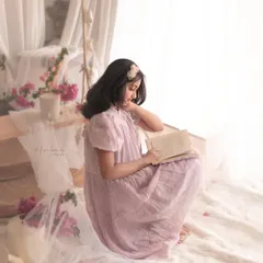 A dreamy, romantic portrait of a young girl reading in a soft, light-filled setting. This image tells a story, capturing the quiet magic of childhood imagination.