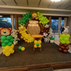 Let's go on a safari! This jungle-themed birthday party features a wooden backdrop, a green and yellow balloon arch, and cute animal cutouts like a tiger, lion, and monkey.