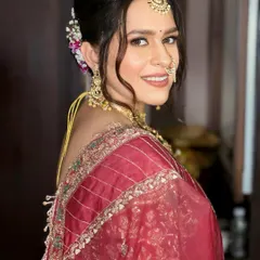 A beautiful bride in a deep red saree, ready for her ceremony. I created a soft, messy updo with fresh flowers and focused on glowing skin and defined eyes for her makeup.