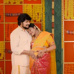 An intimate moment between the expecting couple at their Valaikaappu. The vibrant, colorful backdrop of marigolds and bangles is a signature element of these joyous celebrations.