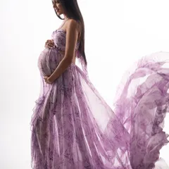 This high-key portrait showcases a beautiful floral lavender gown with a flowing train. The bright, clean background emphasizes the delicate pattern and graceful movement of the fabric.