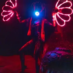The Alien performer illuminated by red light in a dark environment. This demonstrates how our LED shows create a powerful visual impact even in low-light settings.