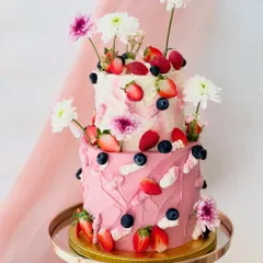 This vibrant two-tiered cake showcases a playful yet elegant design with textured pink buttercream, fresh strawberries, blueberries, and white chrysanthemums. It's a perfect example of how I combine fresh flavours and artistic decoration.