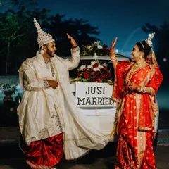 A fun "Just Married" shot with the couple giving a high-five in front of their decorated car, celebrating their new status in style.