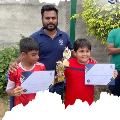 Two of our promising young footballers with their coach, showcasing their individual awards. We make sure to recognize personal growth and outstanding performance alongside team victories.
