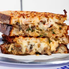 A stacked view of the Cheesy Mushroom Melt, showing the generous filling and the perfectly toasted sourdough. It's a hearty and delicious meal.
