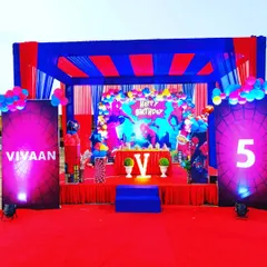 A closer look at the themed stage decoration for a 5th birthday party. The setup includes a central character backdrop, balloon columns, and a small sofa for the cake cutting ceremony.