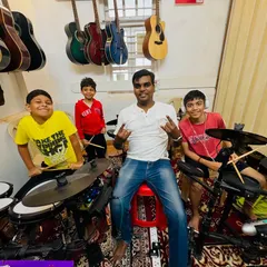 Our drum coach and his students are all smiles and rock signs. The camaraderie and fun in our drum classes are just as important as learning the beats.