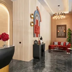 Here is a wider view of a lobby I designed, showing how different elements come together. The vibrant red sofa provides a pop of color against the neutral, fluted walls and dark marble floor. The geometric art and modern chandelier add layers of sophistication and visual interest.