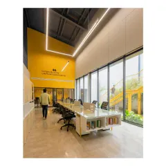 This open-plan workspace for Prime Ply's office in Kannur was designed to foster collaboration and creativity. The high ceilings, abundant natural light from floor-to-ceiling windows, and vibrant color accents create an energizing atmosphere.