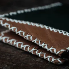 A close-up of the cross-stitching detail on a handmade leather wallet. This is one of the fundamental and durable stitching techniques we teach in our introductory leathercraft workshop.