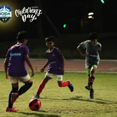 Three of our youngest players enjoying a game under the lights. This is what grassroots football is all about: fun, friends, and a football.