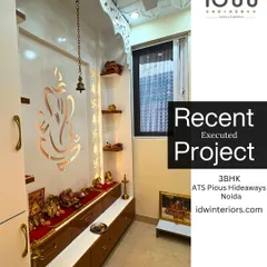 A dedicated pooja room with a large Ganesha motif cut into the back panel. The traditional arch design and warm lighting create a divine and peaceful atmosphere.