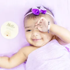 A little bundle of lavender love. This baby girl's shy, sweet smile is perfectly complemented by the soft purple wrap and background.