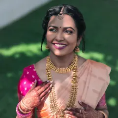 Bathed in sunlight, the bride looks radiant and happy. This portrait captures her beautiful smile, the intricate gold jewelry, and the delicate henna on her hands, all glowing in the natural light.