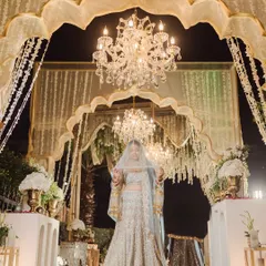 The bride stands beneath a canopy of cascading flowers and crystal chandeliers, a vision of pure elegance. I use the opulent decor and dramatic lighting of the venue to frame her, creating a portrait that feels both grand and deeply personal.