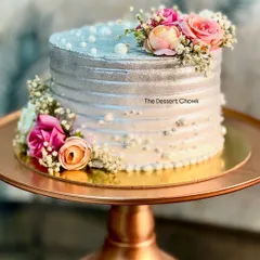 For a 25th wedding anniversary, I designed this stunning silver-dusted tall cake adorned with fresh flowers. The metallic sheen gives it a sophisticated look, perfect for celebrating a silver jubilee.