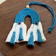 A beautiful, handcrafted rainbow-shaped car charm with evil eye beads. The bright blue and white design with tassels adds a cheerful and protective touch to any car.