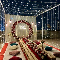 Another angle of the cozy rooftop decoration. The combination of the floral ring, low seating with colorful cushions, and the canopy of lights creates a magical ambiance.