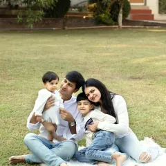 A happy family of four enjoying a picnic-style photoshoot in the park, capturing their relaxed and joyful connection.