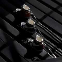 A close-up shot of the colorful sneaker pendants, using specific lighting to highlight the enamel details on each piece against a textured, dark background.