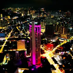 A stunning nighttime aerial shot of "The TOP" skyscraper in Penang, Malaysia, illuminated in vibrant pink. This image captures the dazzling beauty of the city's skyline during my international assignment.