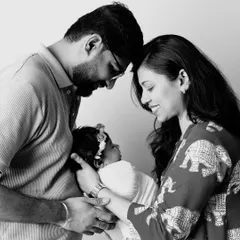 A timeless black and white family portrait. The parents' foreheads touching as they look down at their newborn creates a powerful image of unity and love.