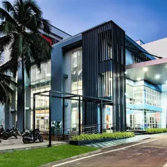A view of the hospital entrance at dusk, where the lighting design enhances the architectural features. The covered drop-off area and clear signage are part of our focus on practical, patient-first design.
