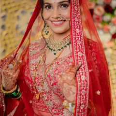 A beautiful portrait of the bride revealing her full reception look. The red lehenga, emerald green jewelry, and flawless makeup come together to create a truly regal appearance.