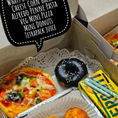 This vegetarian snack box was customized for a birthday girl. It includes cheese corn balls, Alfredo penne pasta, a veg mini pizza, a mini donut, and a tetra-pack juice.