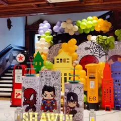 A full view of the action-packed superhero birthday bash. The setup includes a colorful city skyline, character plinths, and a balloon arch, creating an exciting environment for all the little heroes.
