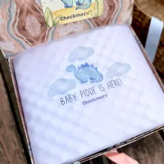 The unboxing experience is part of the gift. Here, personalized tissue paper with a dinosaur motif announces "Baby Pidde is Here," creating a special moment of discovery.