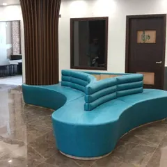 A custom-designed three-way curved sofa serves as the centerpiece for this school's reception lounge. The vibrant teal upholstery adds a splash of color, while the ergonomic shape provides comfortable and practical seating for visitors.