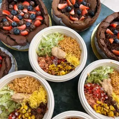 Two of our top-selling desserts: the Flourless Chocolate Cake and our Mexican Rice Bowls. The cake is rich and fudgy, topped with fresh berries and chocolate balls for a decadent treat.