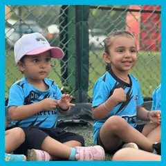 Two friends sitting side by side, fully engaged in the session. We love seeing these little friendships blossom on the field during our summer football camps.