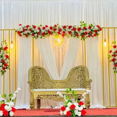 Here’s a more traditional and elegant stage I created, featuring a beautiful ornate sofa for the couple. The backdrop uses clean, golden rectangular frames accented with classic red and white flower arrangements to create a look of timeless grace for your special day.