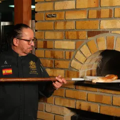 Using the pizza peel to place a dish into the hot brick oven. My years of experience have taught me how to work with the flames to achieve perfect results every time.