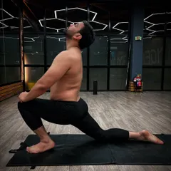 Performing Anjaneyasana (Low Lunge), a deep stretch for the hips and quadriceps. This pose is excellent for improving flexibility and balance.