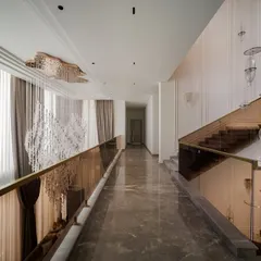 This double-height corridor is designed as a journey between art and architecture. The cascading chandelier and floating glass pendants guide you along the path, with the elegant staircase and marble floors adding to the sense of quiet luxury.