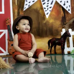 A little cowboy takes a break on the farm. The detailed backdrop and props, like the miniature horse and hay, create an immersive scene.