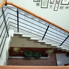 Looking down into the central atrium, a core feature of this tropical modern home. The staircase wraps around this lightwell, which houses indoor plants and brings nature inside.