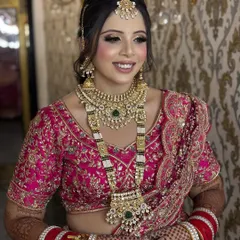 A smiling bride ready for her big day. This regal look in a pink lehenga features soft smokey eyes, a radiant base, and perfectly coordinated jewellery, showcasing a complete and cohesive bridal style.