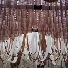 A wide view of the ceiling, showing how the combination of sheer brown lamp shades and draped fabrics in beige and brown creates a warm, intimate, and stylish canopy over the space.
