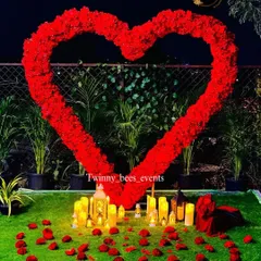 The ultimate romantic setting. We created a large heart-shaped arch of red flowers on a lawn, surrounded by scattered rose petals and glowing electric candles for a magical evening.